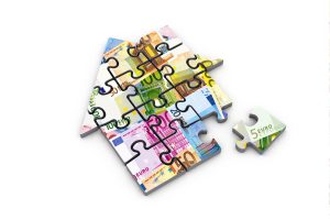Ein Puzzle in Form eines Hauses. Die Puzzleteile sind mit Geldscheinen bedruckt.
