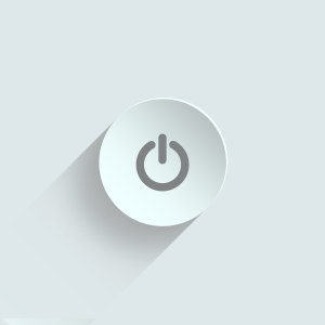 Schalter an technischen Geräten zum ein- und ausschalten. Das Symbol eines Kreises mit einem senkrechten Strich von oben hinein. In grauer Farbe auf weißem Schalter vor weißem Hintergrund.
