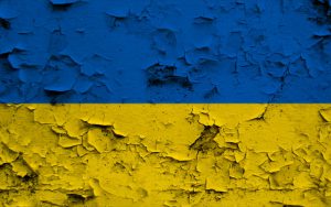 Ukrainische Flagge. Die obere BIldhälfte ist blau. Die unter BIldhälfte ist gelb. Der Untergrund unter der Flagge ist rau und aufgeplatzt; er sieht brüchig aus.