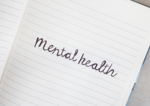 Ein liniertes, weißes Blatt auf dem in Schreibschrift mental health steht.