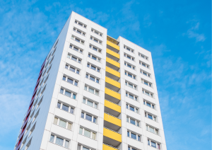 Ein weißes Hochhaus mit einem gelben Mittelelement ragt in den Himmel.