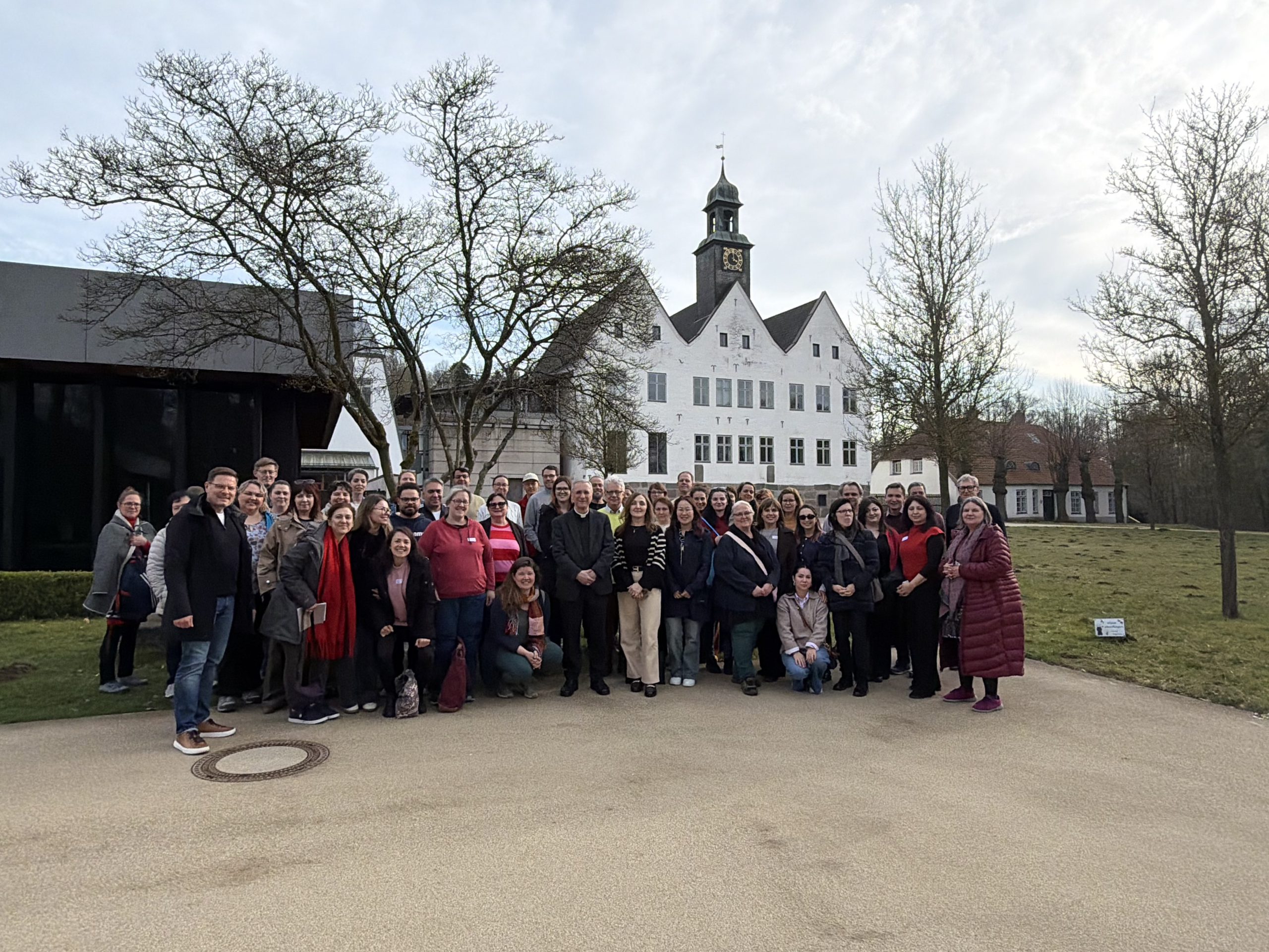 Gruppenbild der Caritas-Migrationsfachtagung Nord-Ost 2026 draußen, mit einem weißen Gebäude im Hintergrund.