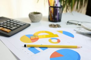 Schreibtisch mit Taschenrechner, Diagrammen und Bleistift