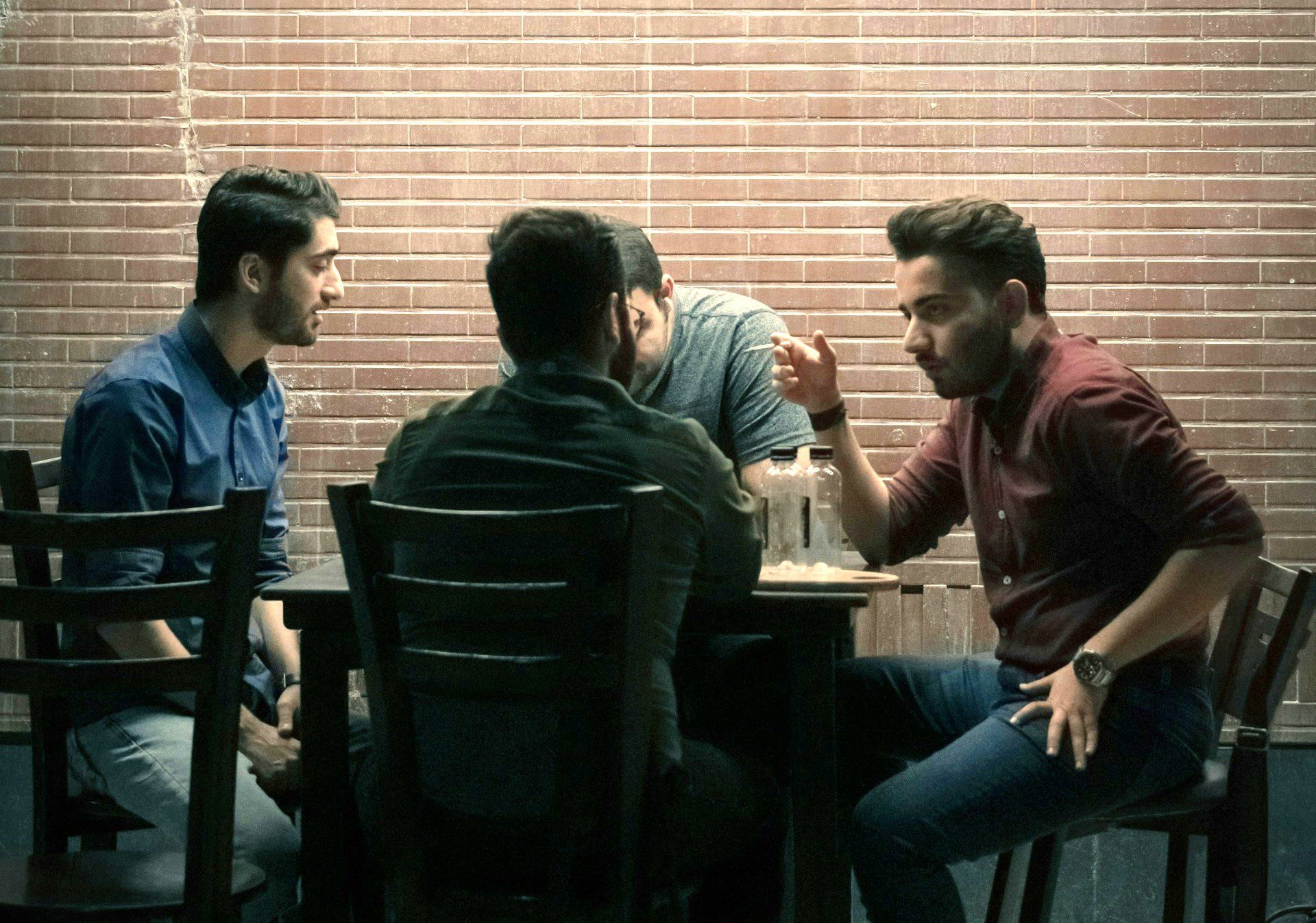 Vier junge Männer sitzen an einem Tisch und reden,