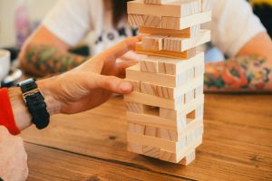 Eine Hand zieht einen Stein aus dem JENGA-Stapelspiel.