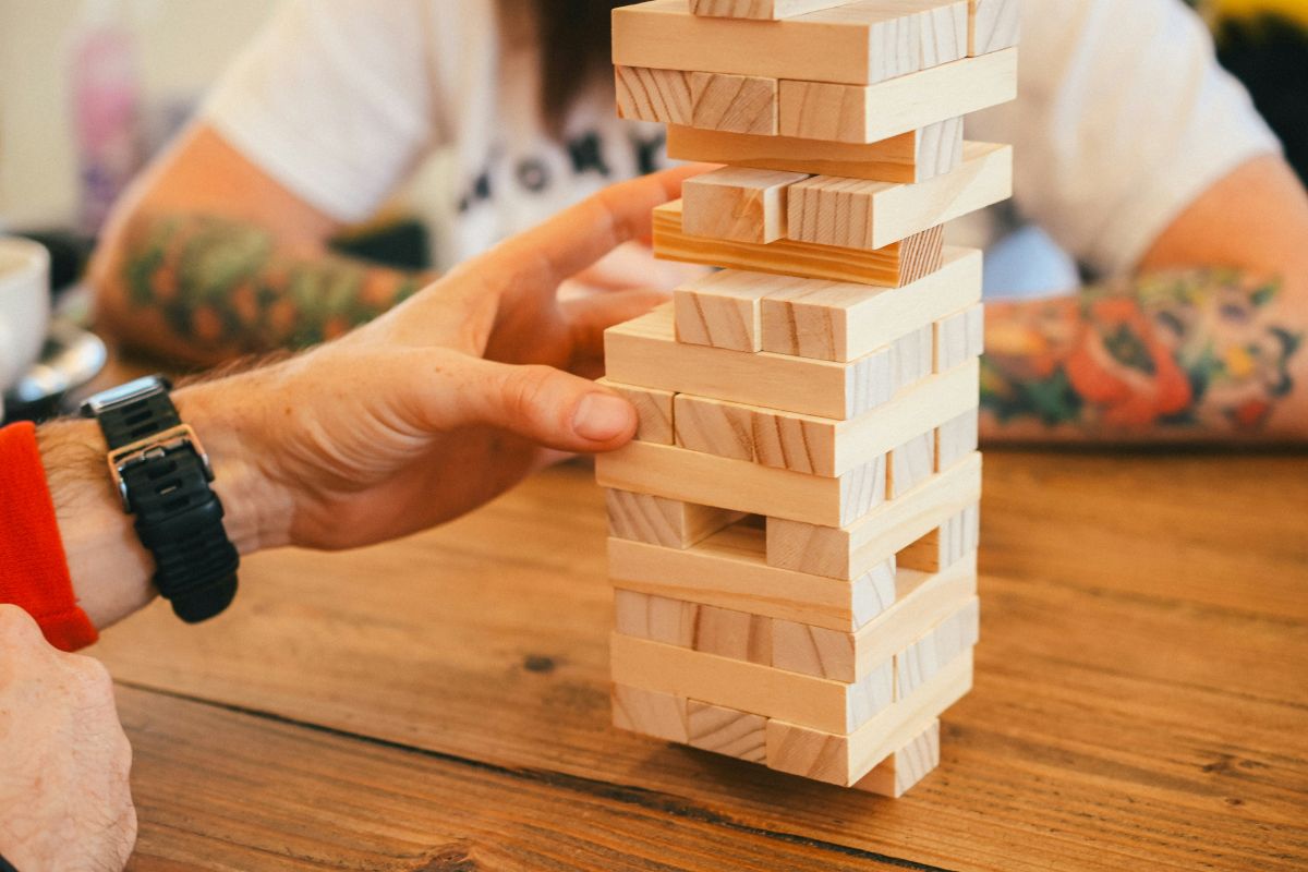 Eine Hand zieht einen Stein aus dem JENGA-Stapelspiel.
